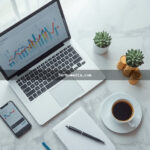 Mesa de trabalho moderna com notebook exibindo gráficos de negócios online, smartphone, moedas e xícara de café representando empreendedorismo digital em 2024