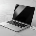 Laptop prateado moderno aberto sobre superfície de mármore branco com etiqueta de desconto de 600 dólares para o Memorial Day 2026